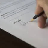 Dłoń podpisuje dokument, być może odpowiedź na pozew.