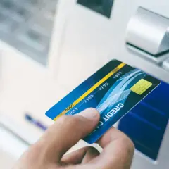 Dłoń z kartą zbliża się do wpłatomatu. Zastanawiasz się, ile można wpłacić we wpłatomacie? Sprawdź limity!