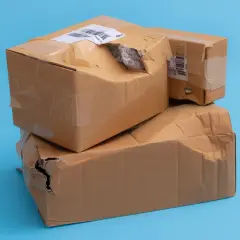 Dwie kartony, jedna na drugiej, z widocznymi uszkodzeniami i dziurami. Wygląda na to, że to uszkodzona paczka InPost.