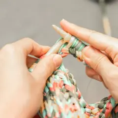 Dłonie dziergają kolorową włóczkę na drutach. Czy na Vinted można sprzedawać handmade? Tak, to świetne miejsce na rękodzieło!