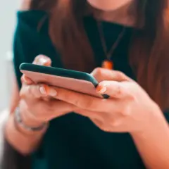 Kobieta pisze na telefonie, zastanawiając się, czy na Vinted można płacić za pobraniem.