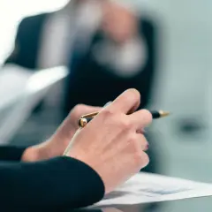 Dłonie trzymające długopis nad dokumentami podczas spotkania w alektum capital ii ag.