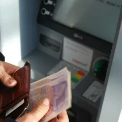 Ręce trzymają portfel z pieniędzmi i kartami przy bankomacie. Sprawdzam saldo przed wypłatą.