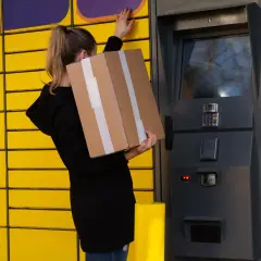 Kobieta z paczką Vinted stoi przy paczkomacie, bo paczka nie zmieściła się do skrytki.