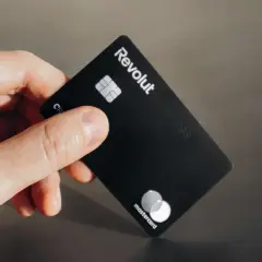Dłoń trzyma czarną kartę Revolut Business. Czy komornik może zająć konto Revolut?