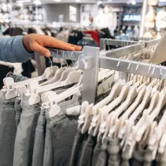 Ręka klienta przegląda spodnie w sklepie Peek & Cloppenburg. Zastanawia się nad zwrotami.