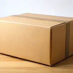 Brązowe pudełko, jak paczka bez etykiety Vinted, czeka na odbiór.