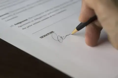 Dłoń podpisuje dokument, być może odpowiedź na pozew.