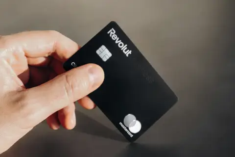 Dłoń trzyma czarną kartę Revolut Business. Czy komornik może zająć konto Revolut?