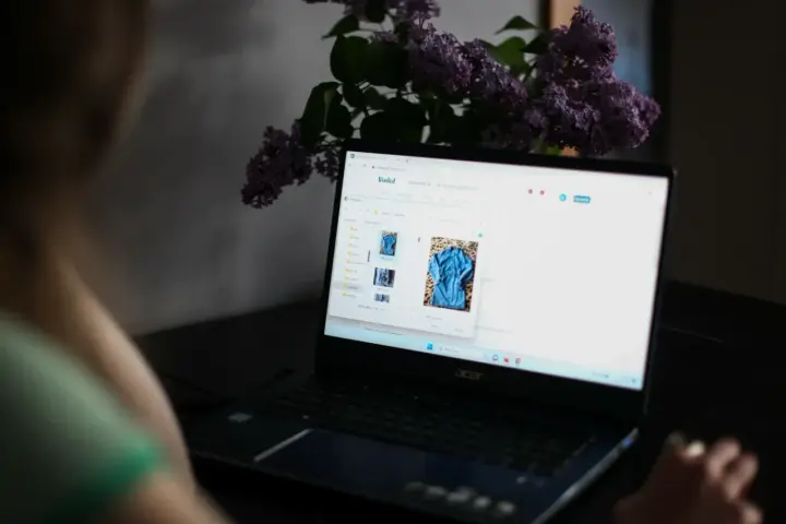 Kobieta przegląda zdjęcia ubrań na laptopie, planując, jak zwiększyć sprzedaż na Vinted.