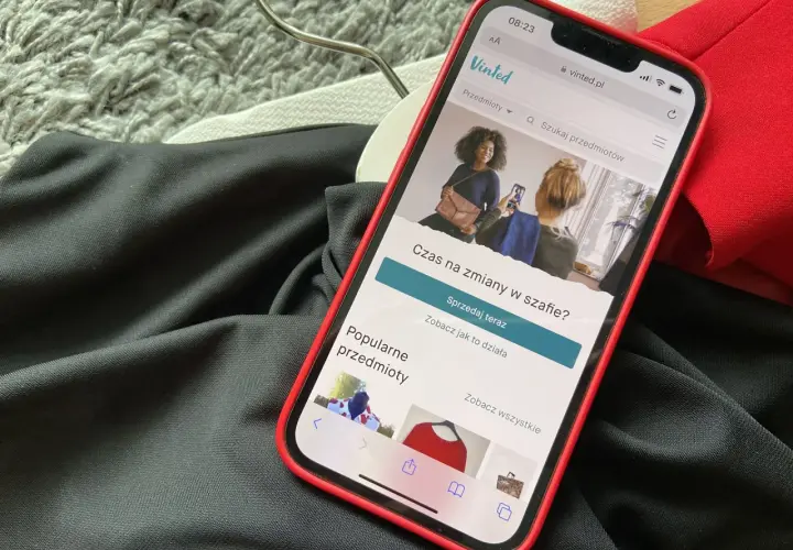 Telefon z aplikacją Vinted leży na ubraniach. Wygląda na to, że portfel Vinted nie działa, bo nie można nic sprzedać.
