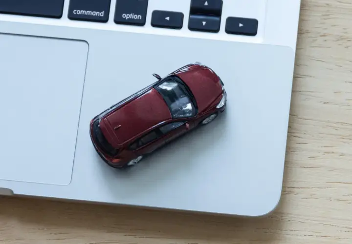 Czerwony samochodzik na laptopie. Zastanawiasz się, ile kosztuje wystawienie samochodu na OLX?