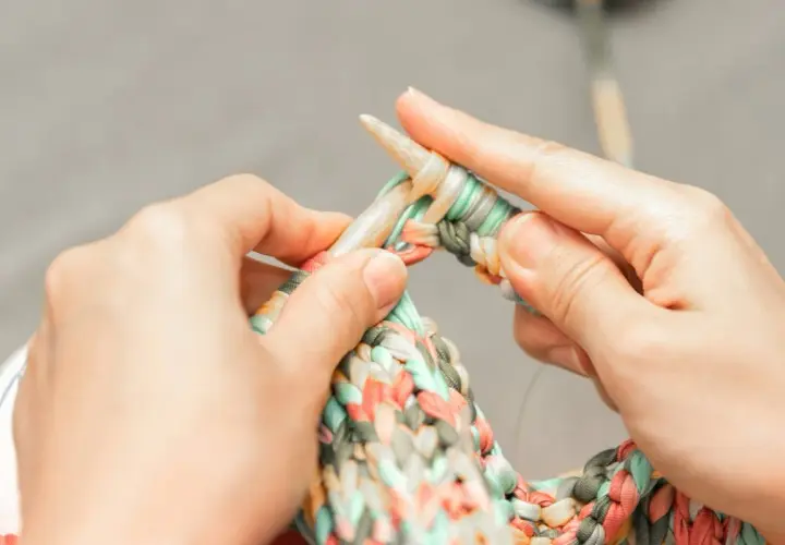 Dłonie dziergają kolorową włóczkę na drutach. Czy na Vinted można sprzedawać handmade? Tak, to świetne miejsce na rękodzieło!