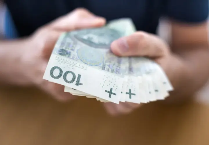 Dłonie trzymają stos banknotów 100 zł. To może być początek drogi do finansowej stabilności, jak kasa stefczyka konsolidacja.