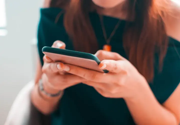 Kobieta pisze na telefonie, zastanawiając się, czy na Vinted można płacić za pobraniem.