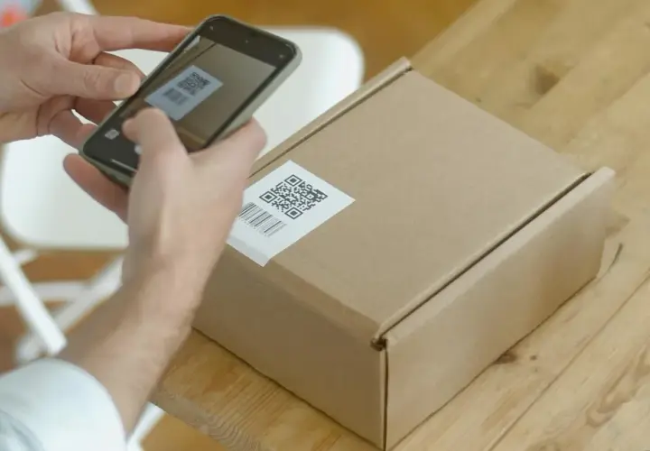 Ręce skanują kod QR na paczce, przygotowując ją do wysyłki w ramach dropshippingu.