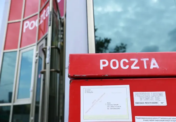 Czerwona skrzynka pocztowa z napisem "POCZTA". Obok niej informacja, ile listów poleconych czeka na poczcie do odbioru.