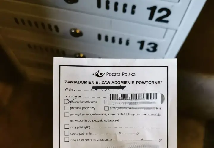Zawiadomienie z Poczty Polskiej o przesyłce poleconej. W tle widoczne skrzynki pocztowe z numerami 12 i 13.