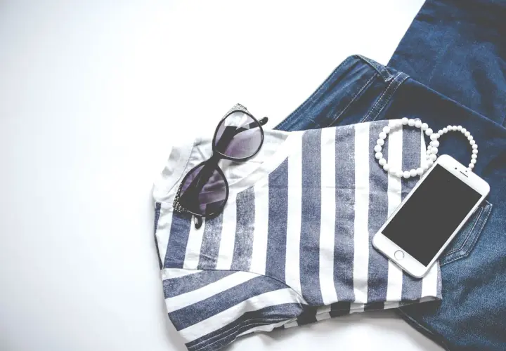 Stylizacja na Vinted: jeansy, bluzka w paski, okulary, bransoletki i telefon. Chcesz wiedzieć, jak obniżyć cenę na Vinted?