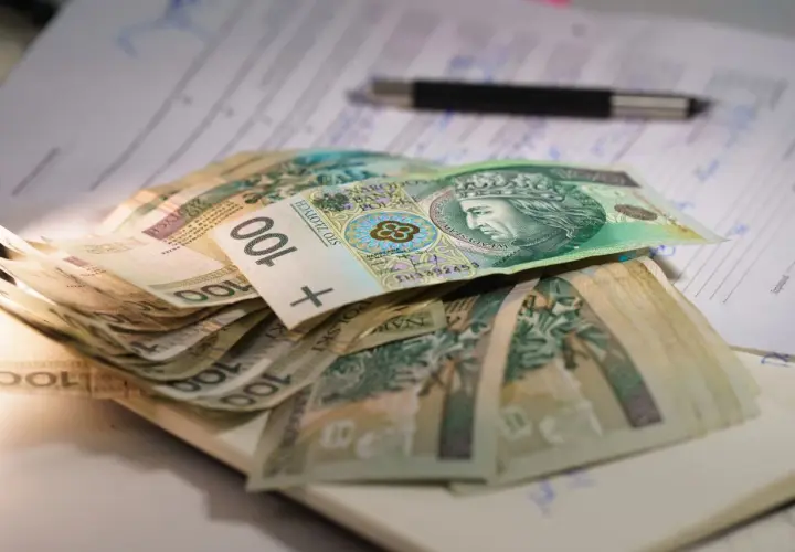 Stos banknotów 100 zł na dokumentach, gotowy na kredyt 50 tys. Długopis leży obok.