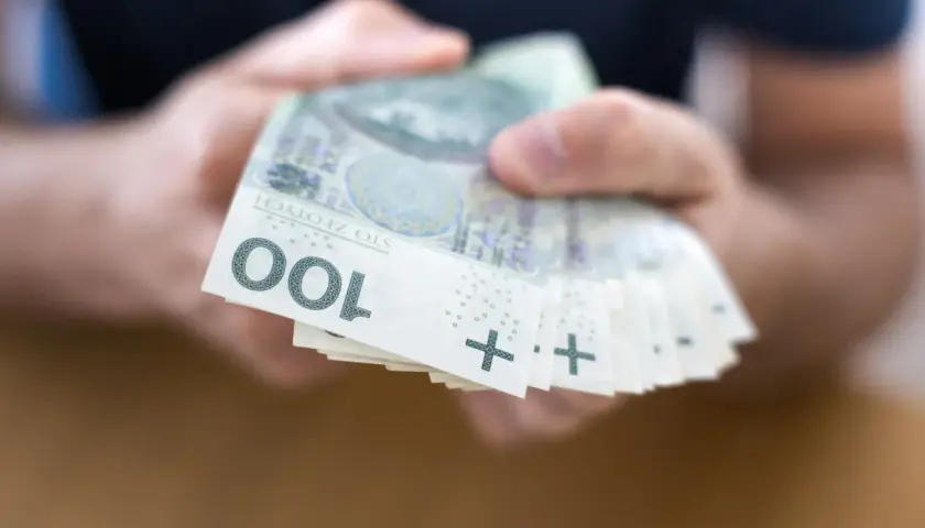 Dłonie trzymają stos banknotów 100 zł. To może być początek drogi do finansowej stabilności, jak kasa stefczyka konsolidacja.