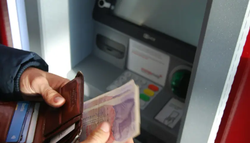 Ręce trzymają portfel z pieniędzmi i kartami przy bankomacie. Sprawdzam saldo przed wypłatą.
