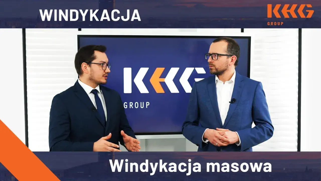 Dwóch mężczyzn w garniturach stoi przed ekranem z logo KK GROUP.