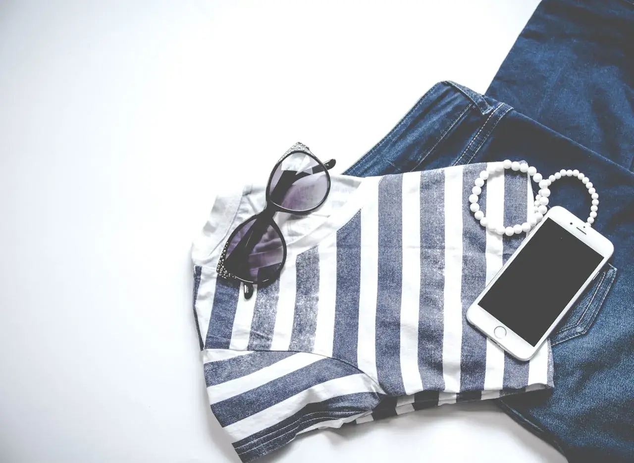 Stylizacja na Vinted: jeansy, bluzka w paski, okulary, bransoletki i telefon. Chcesz wiedzieć, jak obniżyć cenę na Vinted?