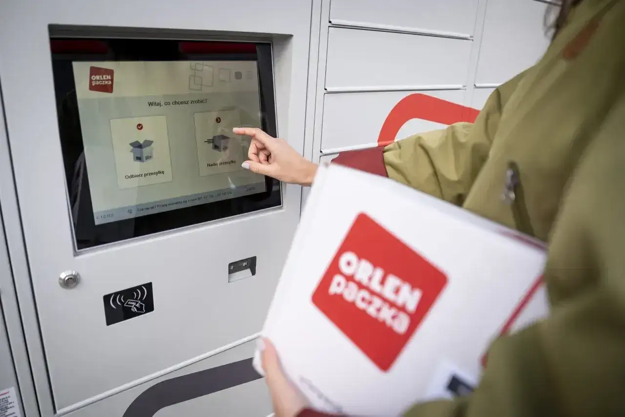 Kobieta z paczką Orlen Paczka obsługuje paczkomat. Czy Orlen Paczka dostarcza w soboty? Sprawdźmy!