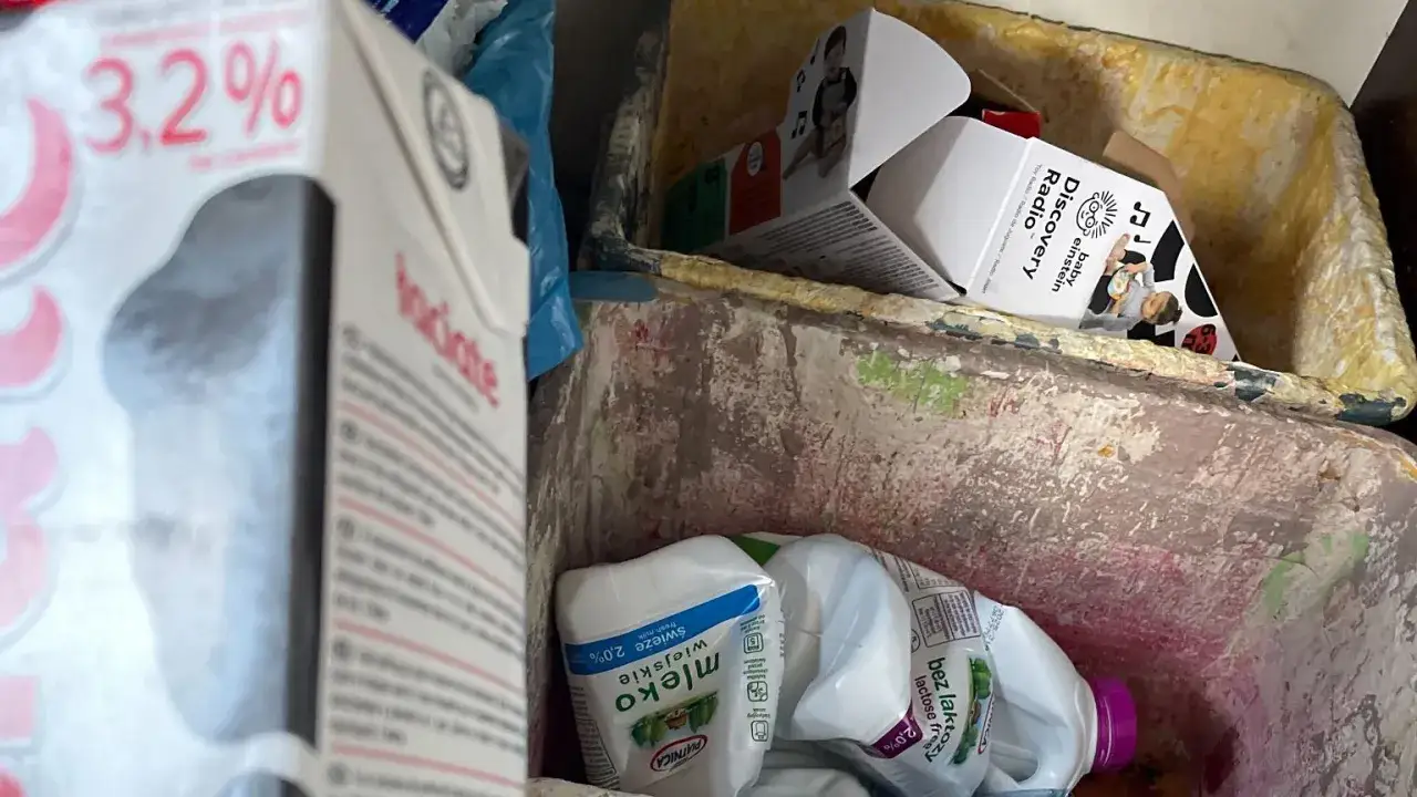 Karton po mleku i inne opakowania w koszu na śmieci. Pytanie: gdzie wyrzucić karton po mleku? Odpowiedź: do odpowiedniego pojemnika na odpady.