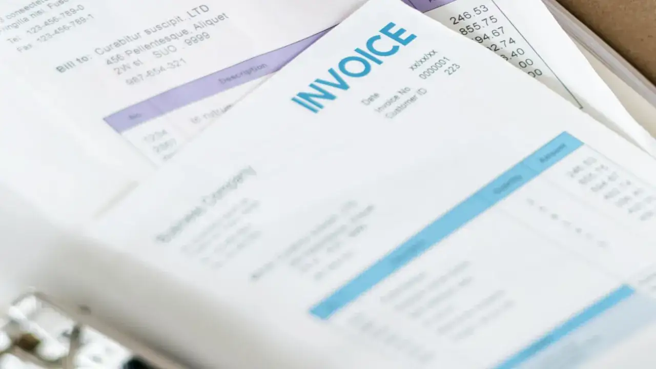 Stos dokumentów, w tym faktura (INVOICE) i rachunek, przygotowywane do odprawy celnej.